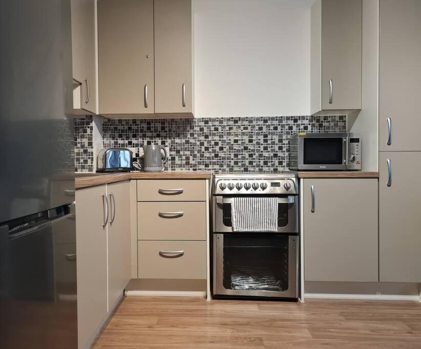 eine Küche mit weißen Schränken und einem Herd mit Backofen in der Unterkunft Stylish Apartment near Tower Bridge in London