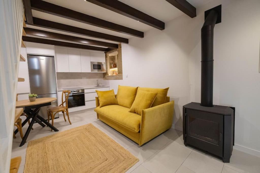 a living room with a yellow couch and a stove at Casa Soledá e Pepa in Outes