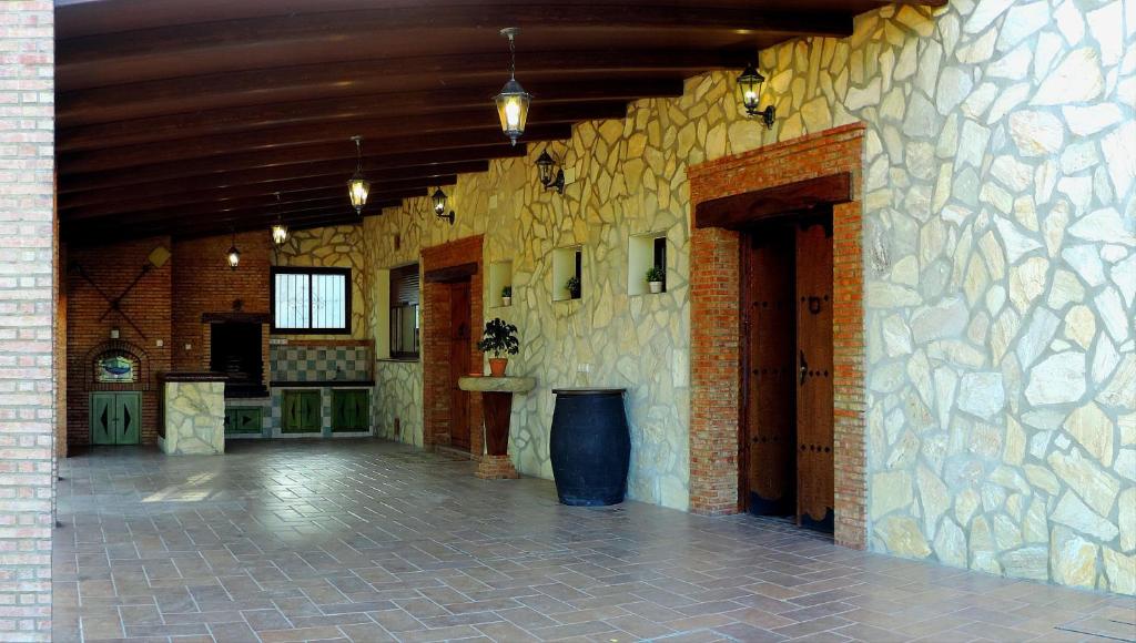 Habitación grande con pared de piedra y pasillo. en Casa Rural Las Provincias, en Prado del Rey