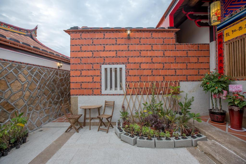 a patio with a table and chairs and a brick wall at Zhu Shan Grandee B&amp;B in Jincheng