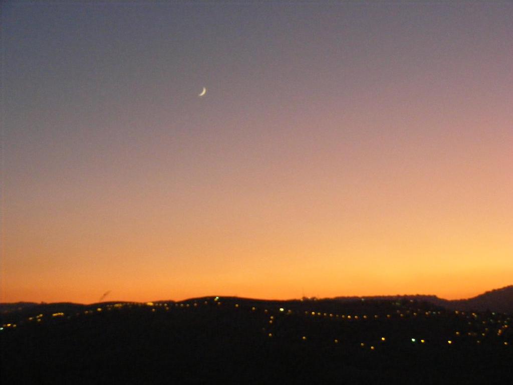 a moon in the sky over a city at sunset at Nof Canaan in Kfar Adumim