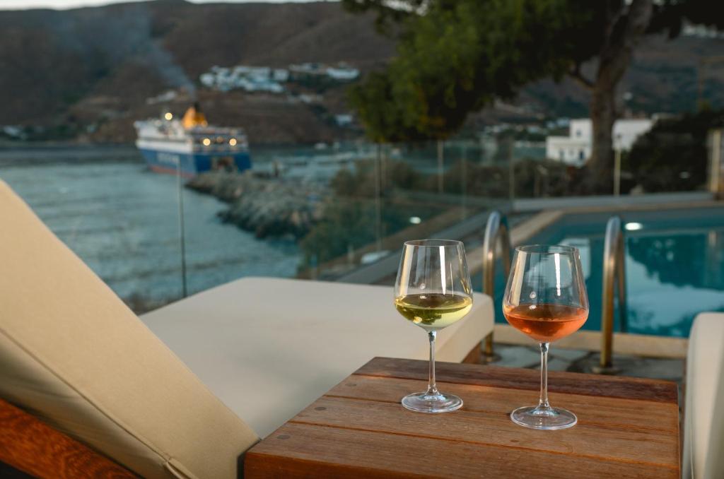 two glasses of wine sitting on a wooden table at Yperia Hotel in Aegiali