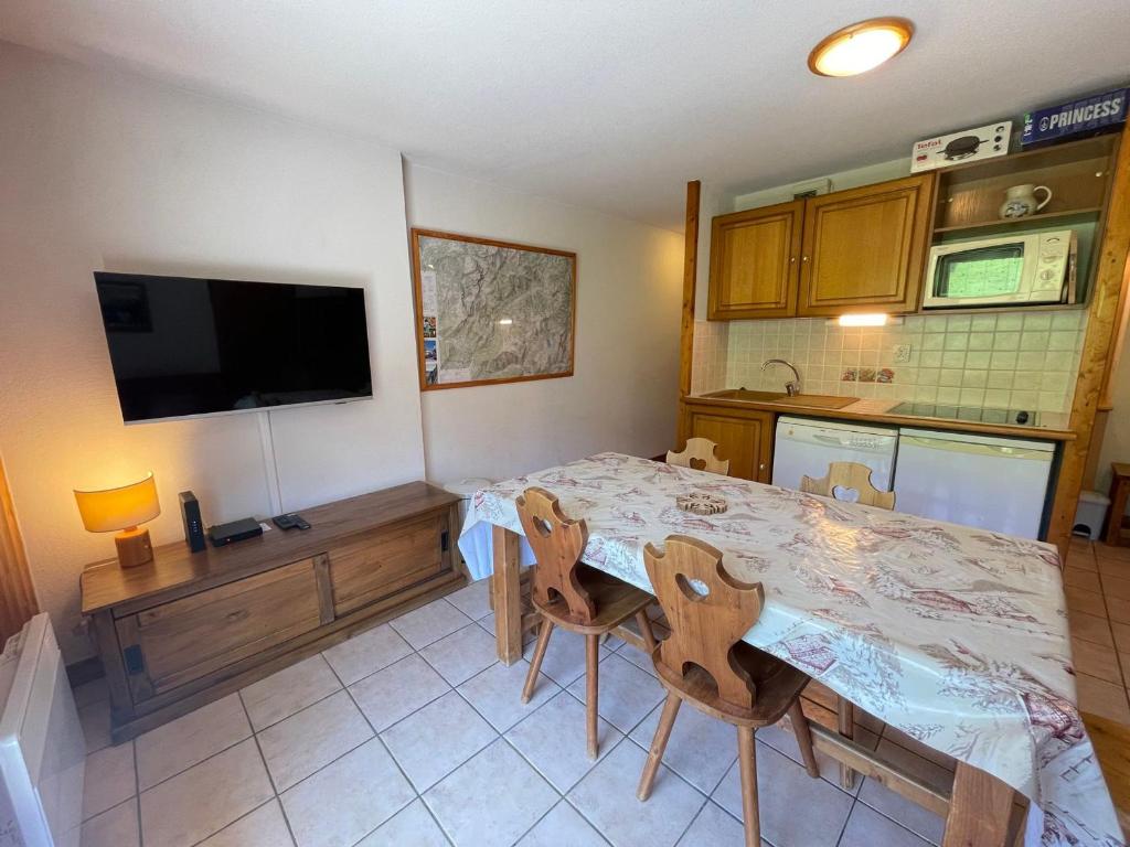 une cuisine avec une table et des chaises et une télévision dans l'établissement Appartement cosy au pied des pistes avec balcon, wifi et parking - FR-1-505-92, à Flumet