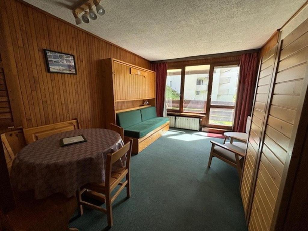 Cette chambre comprend une table et un canapé vert. dans l'établissement Studio 25m² à 20M des pistes, balcon sud/ouest, 4 pers., TV - FR-1-449-144, à Tignes