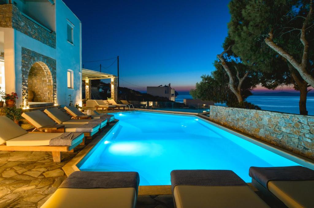 a swimming pool with chaise lounge chairs next to a building at Yperia Hotel in Aegiali