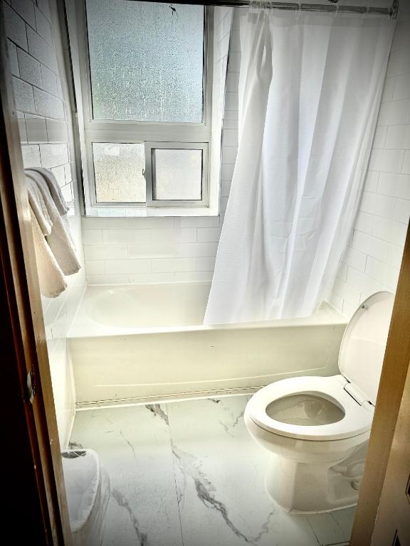 a white bathroom with a toilet and a window at Royal Oak Inn in Toronto