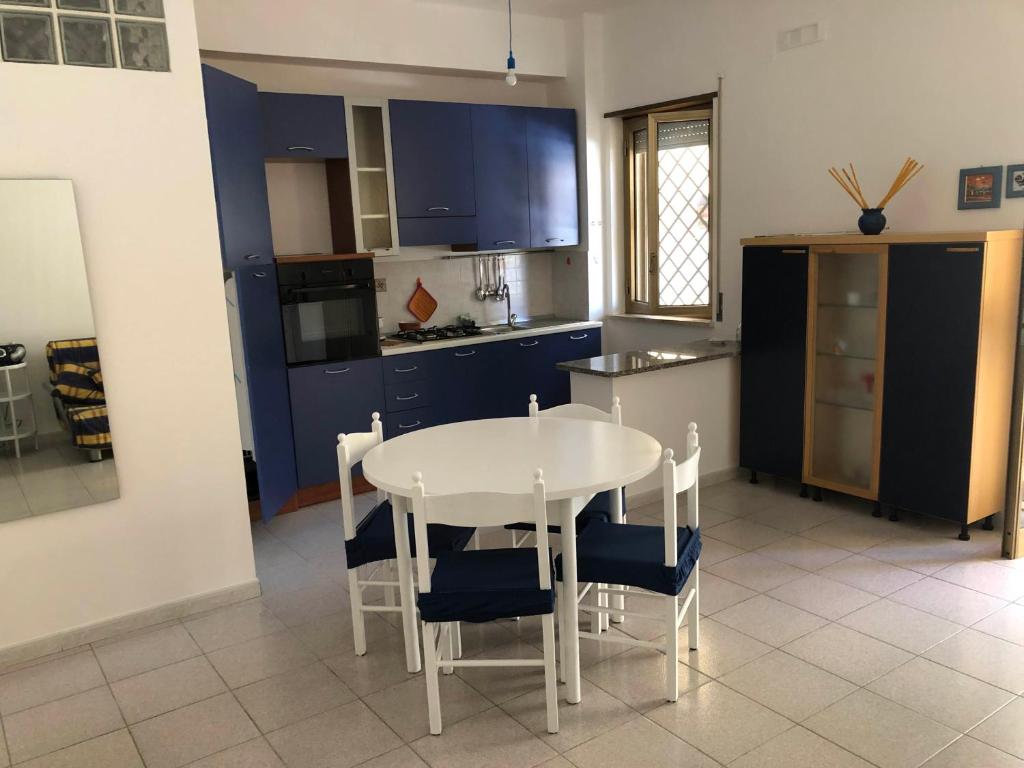 een keuken met een witte tafel en blauwe kasten bij Casa Marylu con giardino in Marina di Schiavonea