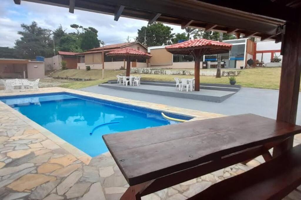 a pool with a picnic table and umbrellas at Chácara Harmonia Pouso Alegre in Pouso Alegre