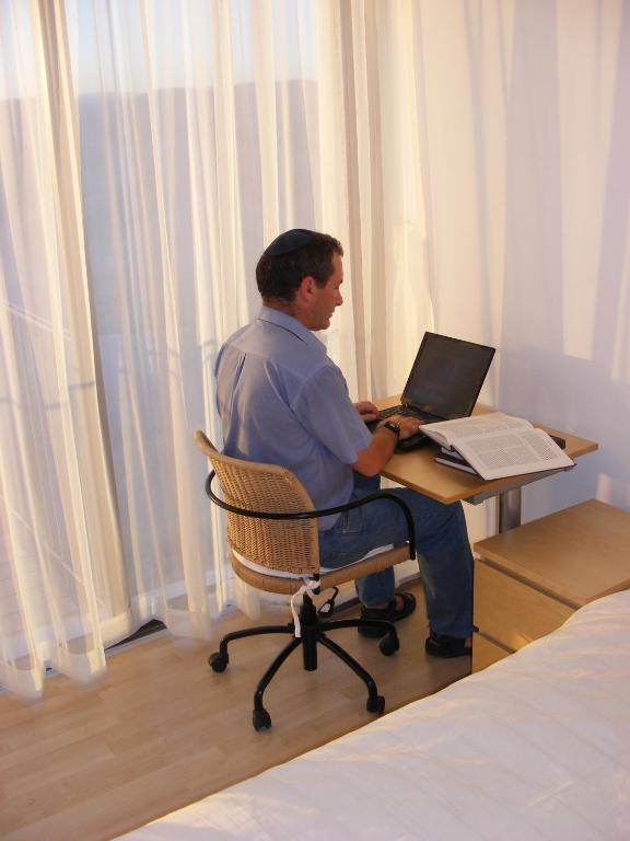 a man sitting at a desk with a laptop at Nof Canaan in Kfar Adumim