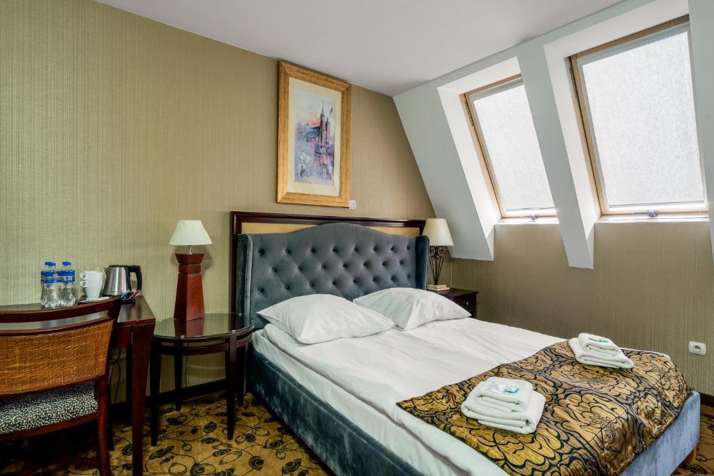 een slaapkamer met een bed, een tafel en ramen bij Great Polonia Kraków Kazimierz in Krakau