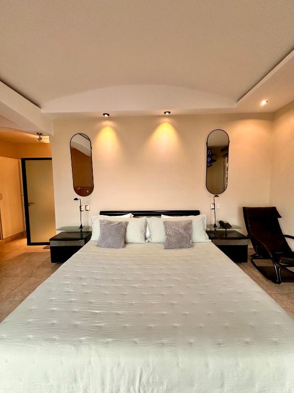 a bedroom with a large white bed with two mirrors at Departamento en el centro de Apatzingán in Apatzingán de la Constitución