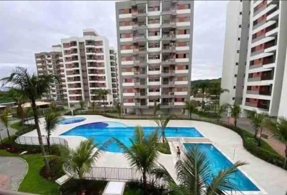 ein großer Swimmingpool mit Palmen und Gebäuden in der Unterkunft Luxuoso AP no Martim Praia Clube - Martim de Sá in Caraguatatuba