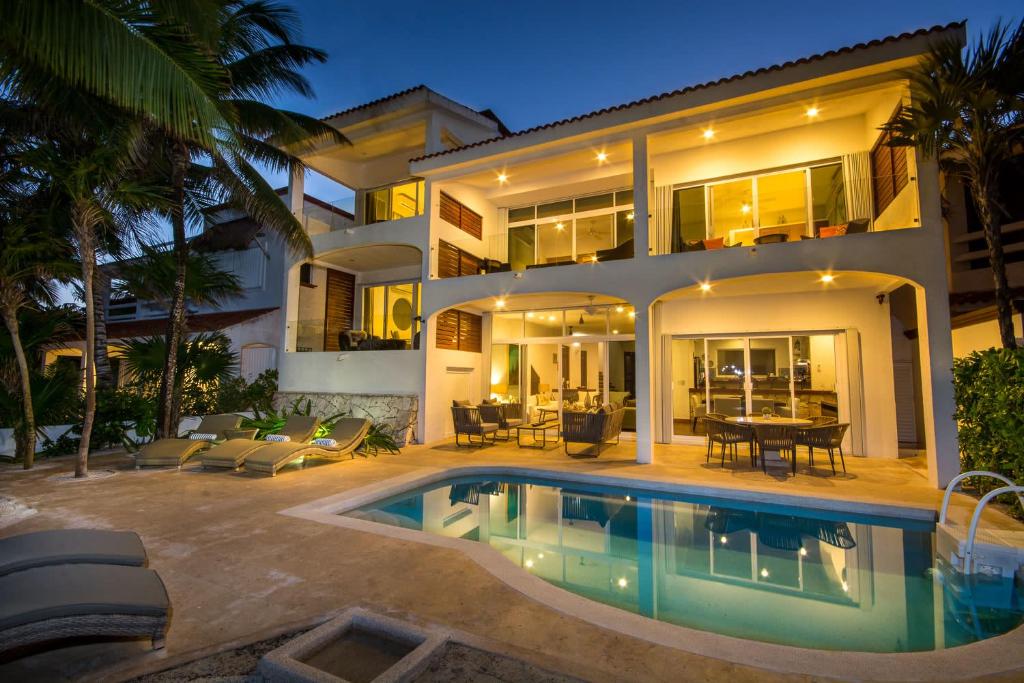 a house with a swimming pool in front of it at Beachfront with Private Staff in Gated Community in Akumal
