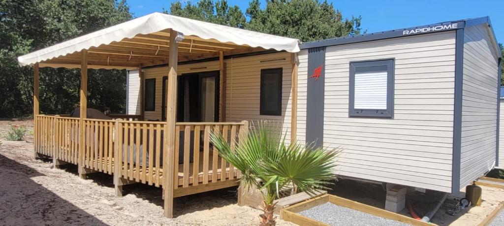 une petite cabane en bois avec un auvent et une plante dans l'établissement MOBILE-HOME au COEUR des LANDES, à Herm