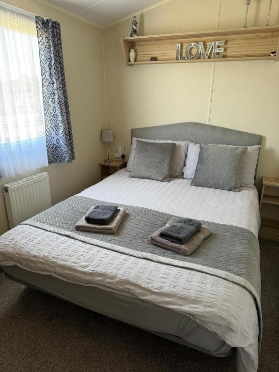 a bedroom with a large bed with two towels on it at Comfy Cosy Caravan_Romney Sands in Littlestone-on-Sea