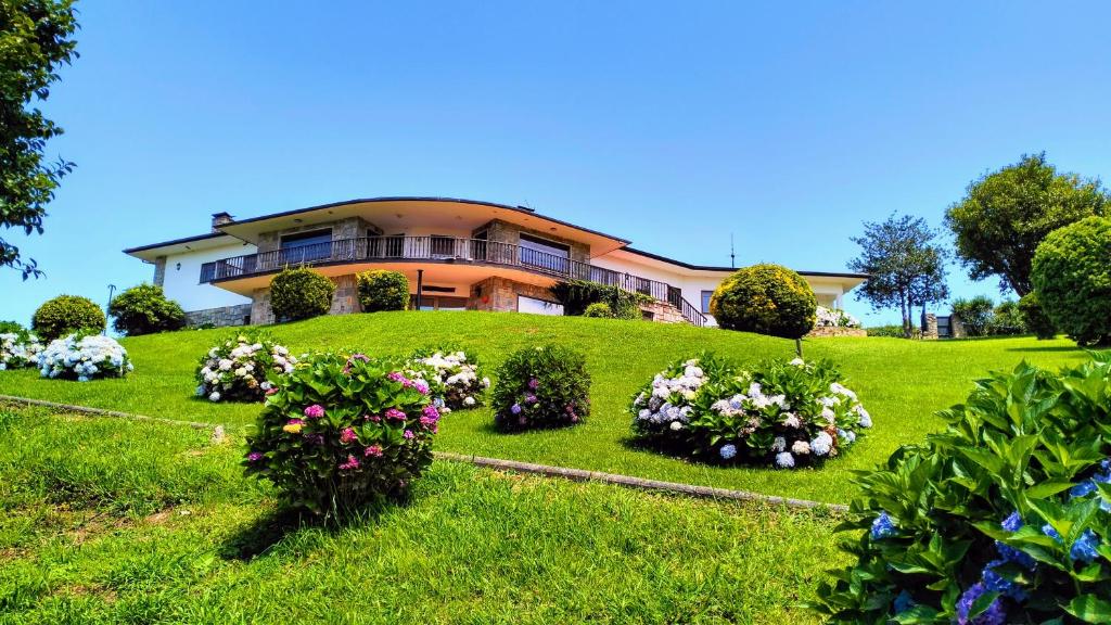 a house on a hill with flowers in the grass at Finca Tolombreo Casa Gabriel in Cudillero