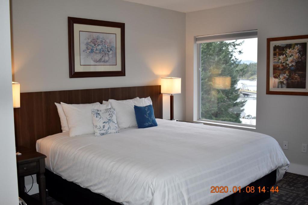 a bedroom with a large white bed with a window at High Pont Resort in Quathiaski Cove