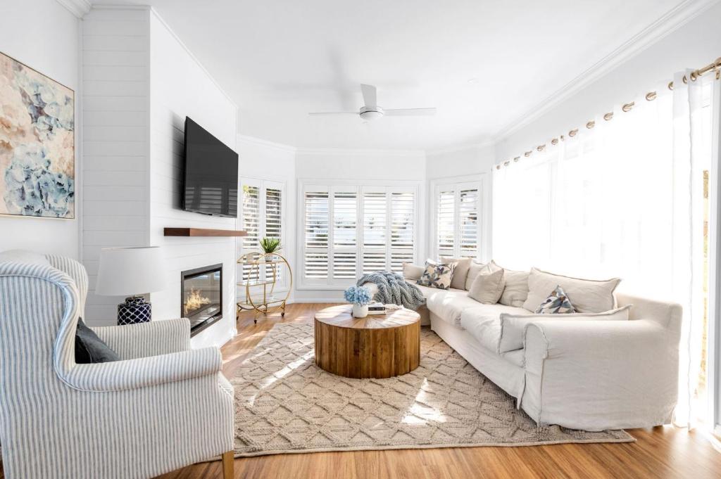 a white living room with a white couch and a table at Berry Vista - By Berry Getaways in Berry