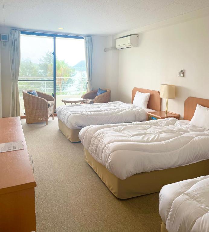 a hotel room with three beds and a window at Kerama Blue Resort in Zamami