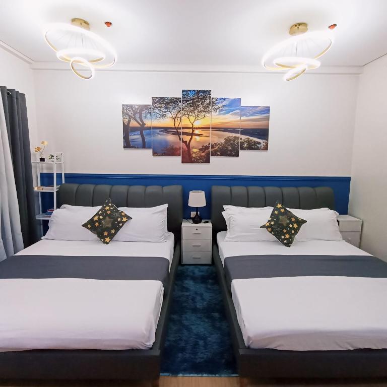 two beds in a room with two paintings on the wall at Anne's Place at Hope Residences - SMDC Condo Beside SM Trece in Trece Martires