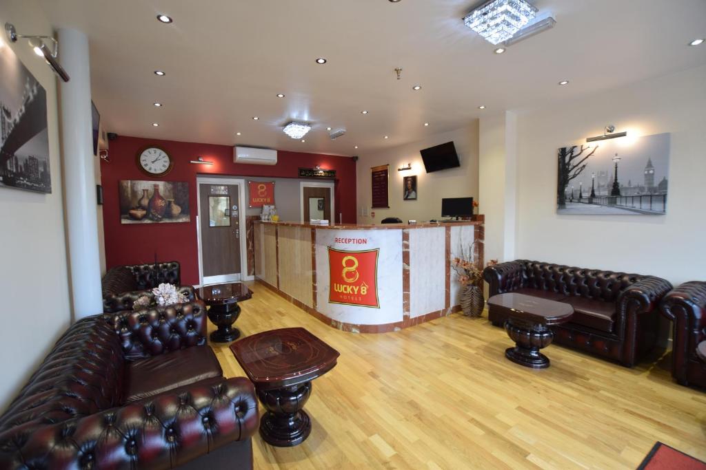 a waiting room with leather couches and a bar at Lucky 8 Hotel in Ilford