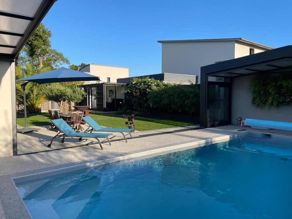 une piscine avec deux chaises et un parasol dans l'établissement Conteneur studio, à Saint-Père