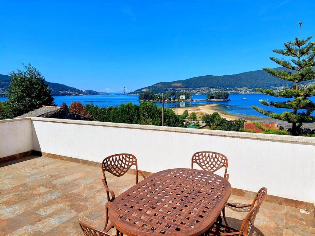 ein Tisch und Stühle auf einem Balkon mit Blick auf das Wasser in der Unterkunft Casa Loural in Redondela