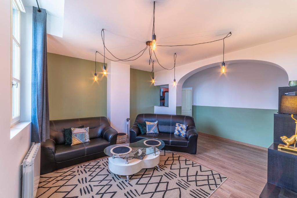 un salon avec deux canapés en cuir et une table dans l'établissement La Halte Parodienne - Appt avec vue sur le canal, à Paray-le-Monial