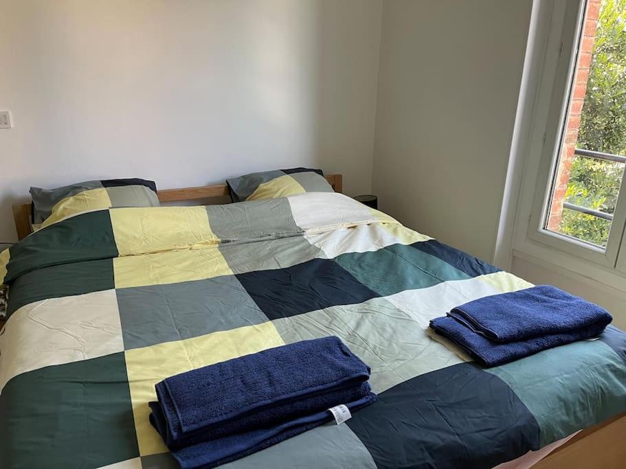 a bed with two blue towels on top of it at Jolie Meulière à 15 min de Paris in Deuil-la-Barre