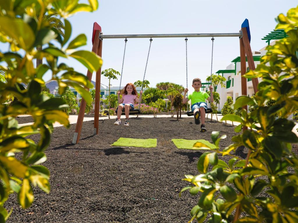 a boy and a girl sitting on a swing at MYND Yaiza in Playa Blanca