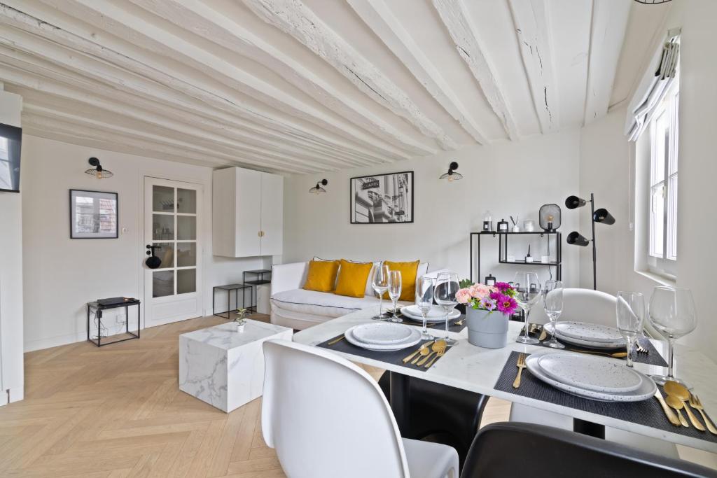 un salon blanc avec une table et des chaises dans l'établissement Élégant Appartement près du Musée du Louvre et du Jardin des Tuileries Free Netflix, à Paris