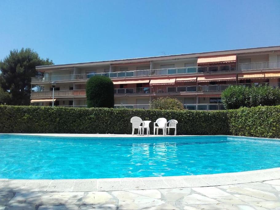 une piscine avec deux chaises et un bâtiment dans l'établissement Joli studio Cap d'Antibes, à Antibes