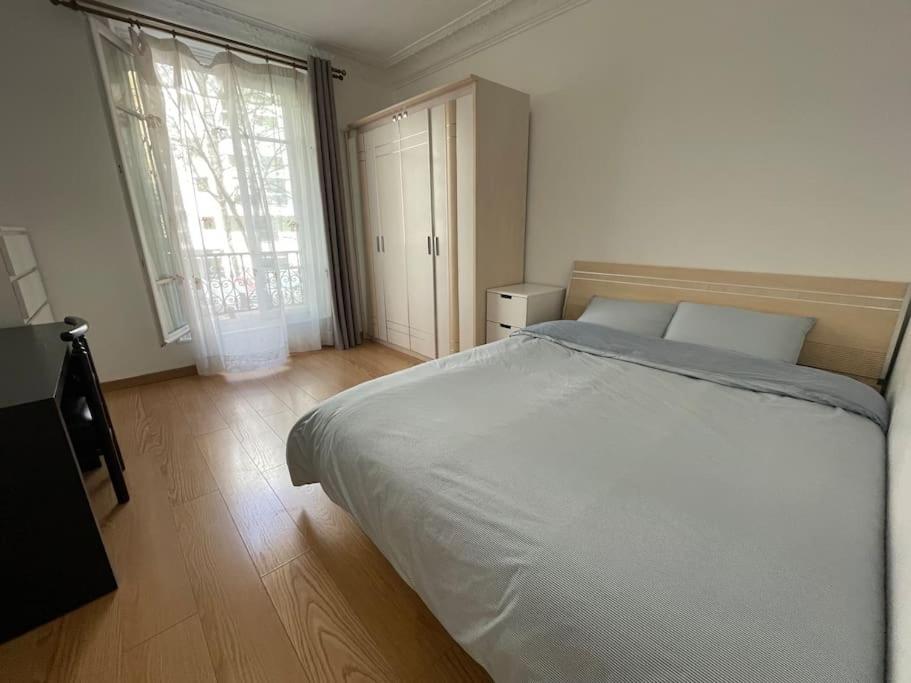 une chambre avec un grand lit et une grande fenêtre dans l'établissement Appartement confort Paris 15ème, à Paris
