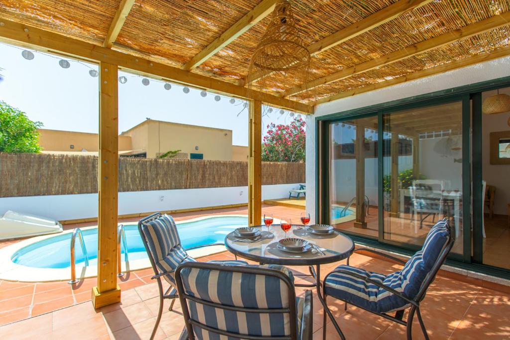 eine Terrasse mit Tisch und Stühlen und einem Pool in der Unterkunft VILLA Paraiso del sol in La Oliva