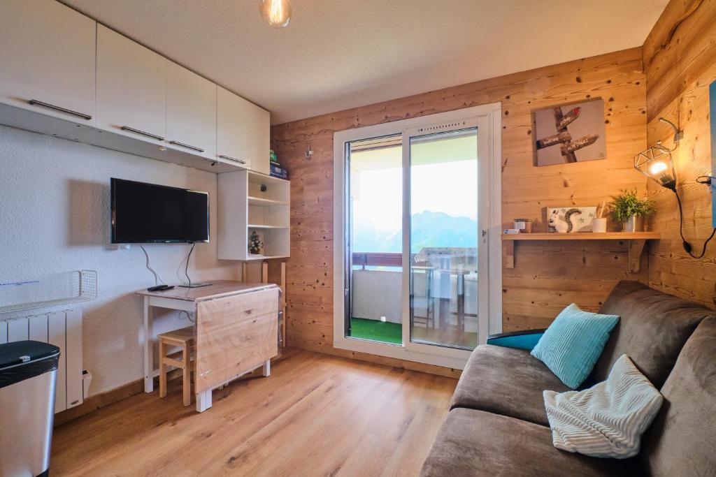 un salon avec un canapé et une grande fenêtre dans l'établissement Les Ours Bleus, à L'Alpe-d'Huez