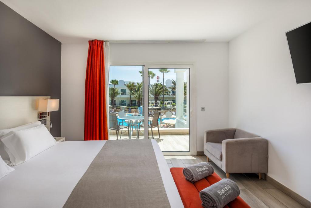 a hotel room with a bed and a view of a patio at Barceló Corralejo Sands in Corralejo