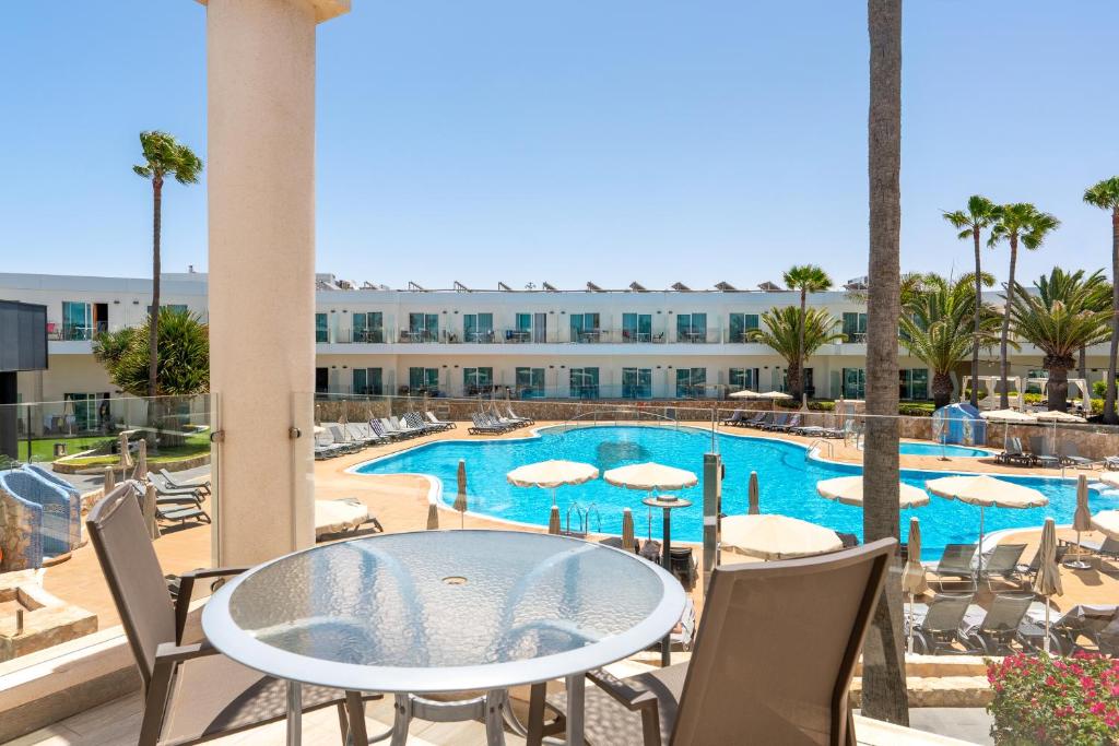 a patio with a table and chairs and a swimming pool at Barceló Corralejo Sands in Corralejo