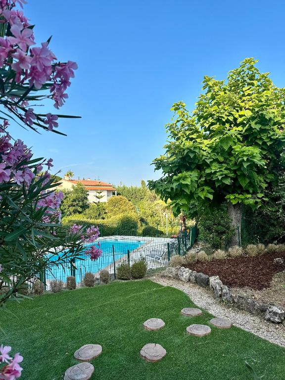 un jardin avec une piscine et un arbre dans l'établissement T2 Mandelieu Cannes - Résidence calme -piscine - proche commodités, à Mandelieu-la-Napoule