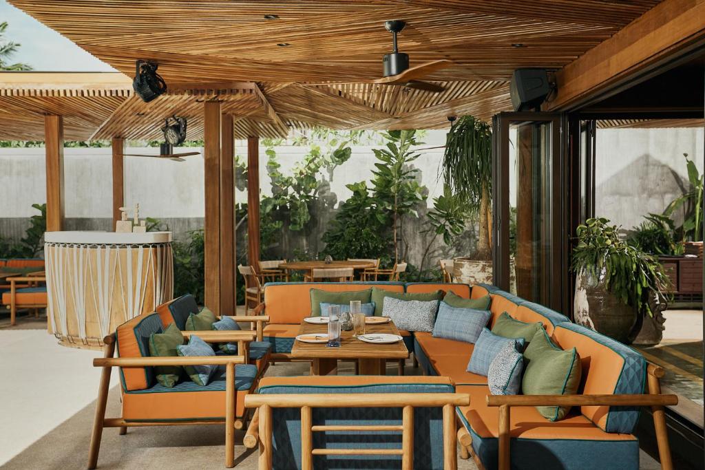 a patio with a couch and tables and chairs at Barcelo Coconut Island, Phuket in Phuket Town