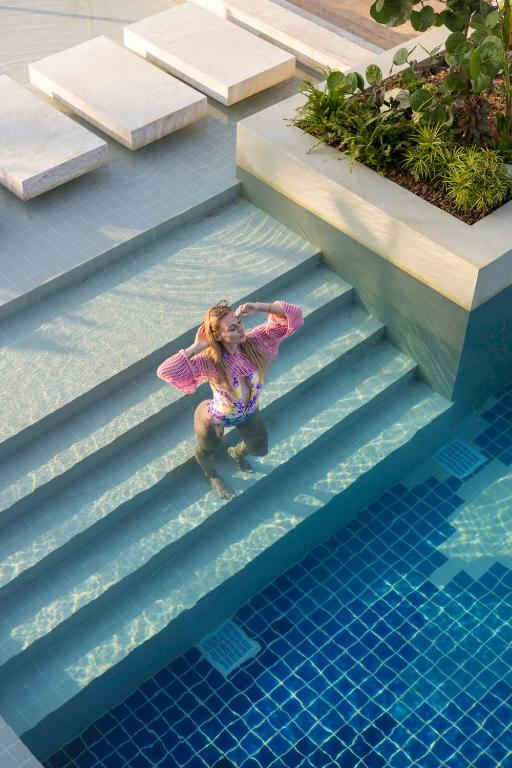 a little girl is standing on some stairs next to a swimming pool at Barcelo Coconut Island, Phuket in Phuket Town