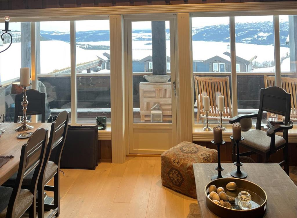 ein Wohnzimmer mit Tisch und großem Fenster in der Unterkunft Ullsheim Grendehytte in Beitostøl