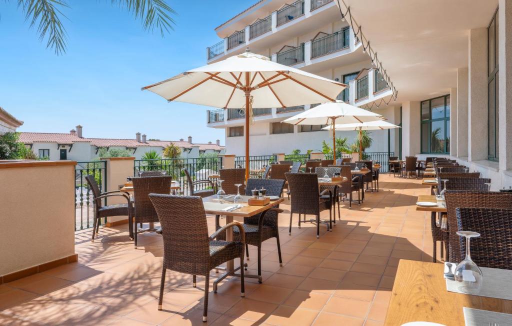 an outdoor patio with tables and chairs and umbrellas at Valentin Son Bou in Son Bou