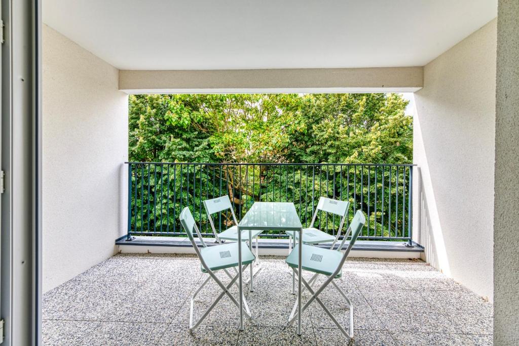 une table en verre et des chaises sur un balcon dans l'établissement Moulin à Vent A22 - Appt pour 4p, à Bondy
