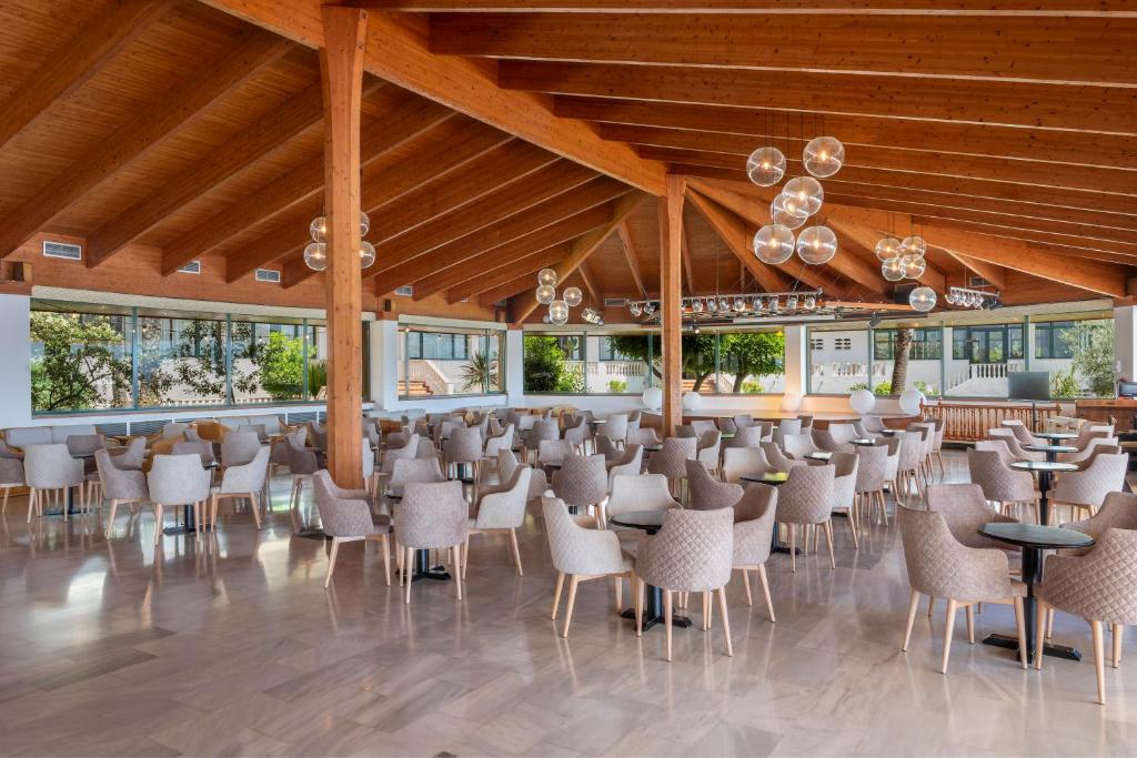 a dining room with chairs and tables and windows at Valentin Son Bou in Son Bou