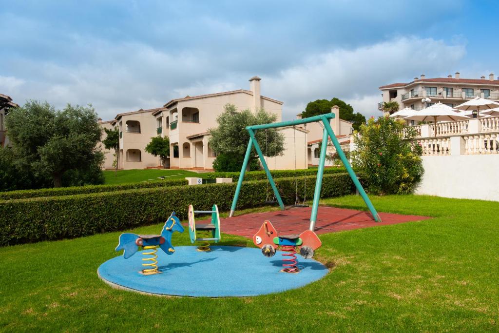 a playground with two swings in a yard at Valentin Son Bou in Son Bou