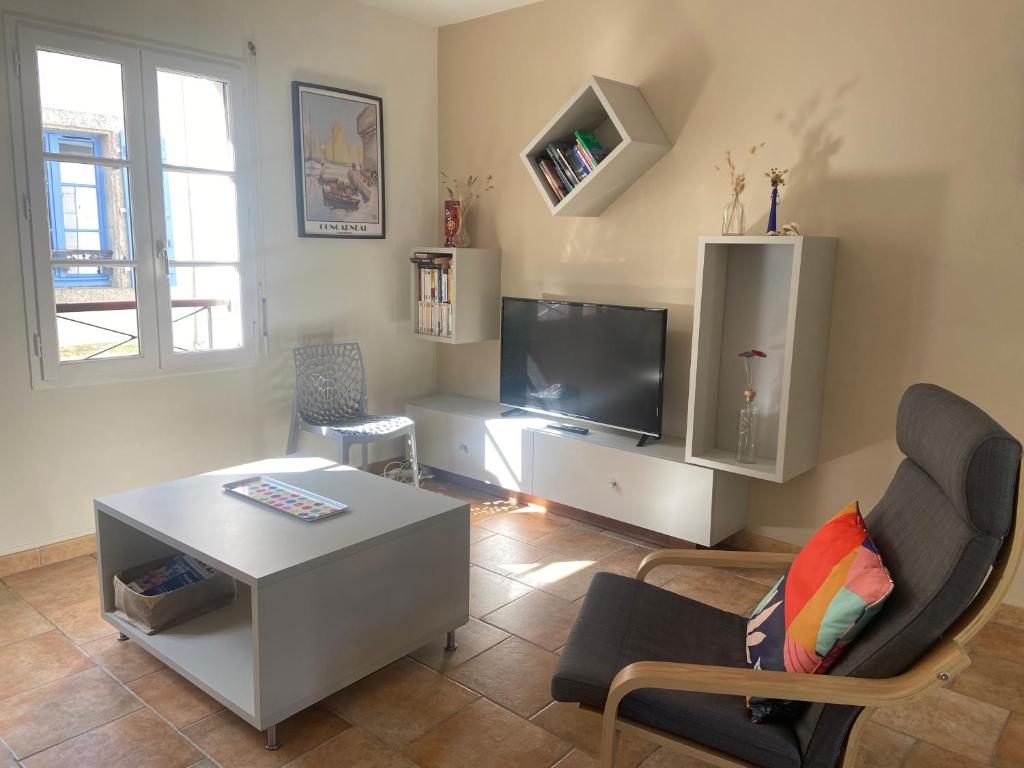 ein Wohnzimmer mit Tisch und Fernseher in der Unterkunft Maison de centre-ville avec grande terrasse in Concarneau
