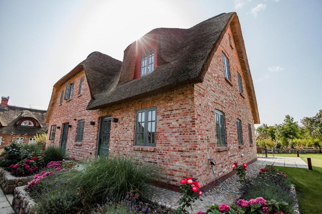 a brick house with a roof and some flowers at Letj Ferhaaling in Oldsum