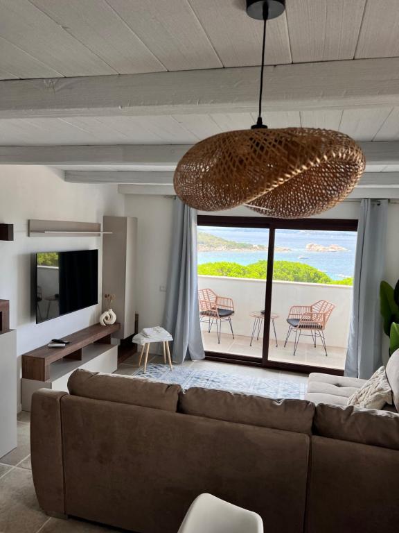 un soggiorno con un divano e una grande finestra di Corallo by Residence Rena Bianca a Baja Sardinia