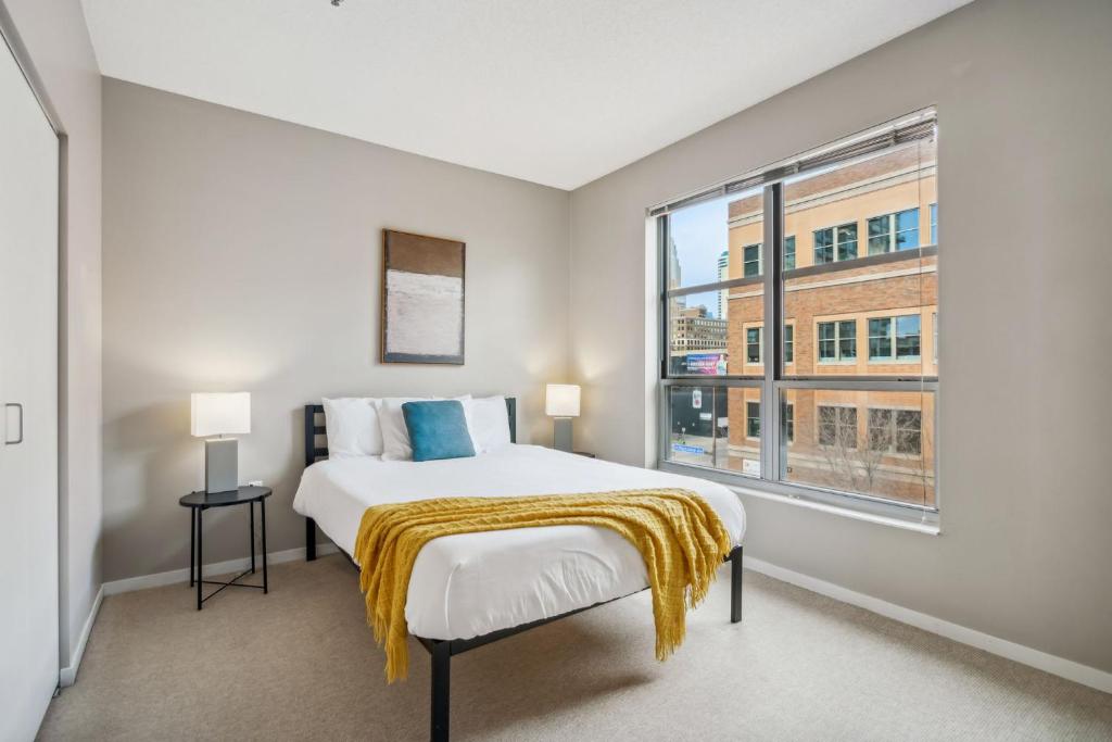 een slaapkamer met een bed en een groot raam bij Two CozySuites Mill District #04 & 01 in Minneapolis