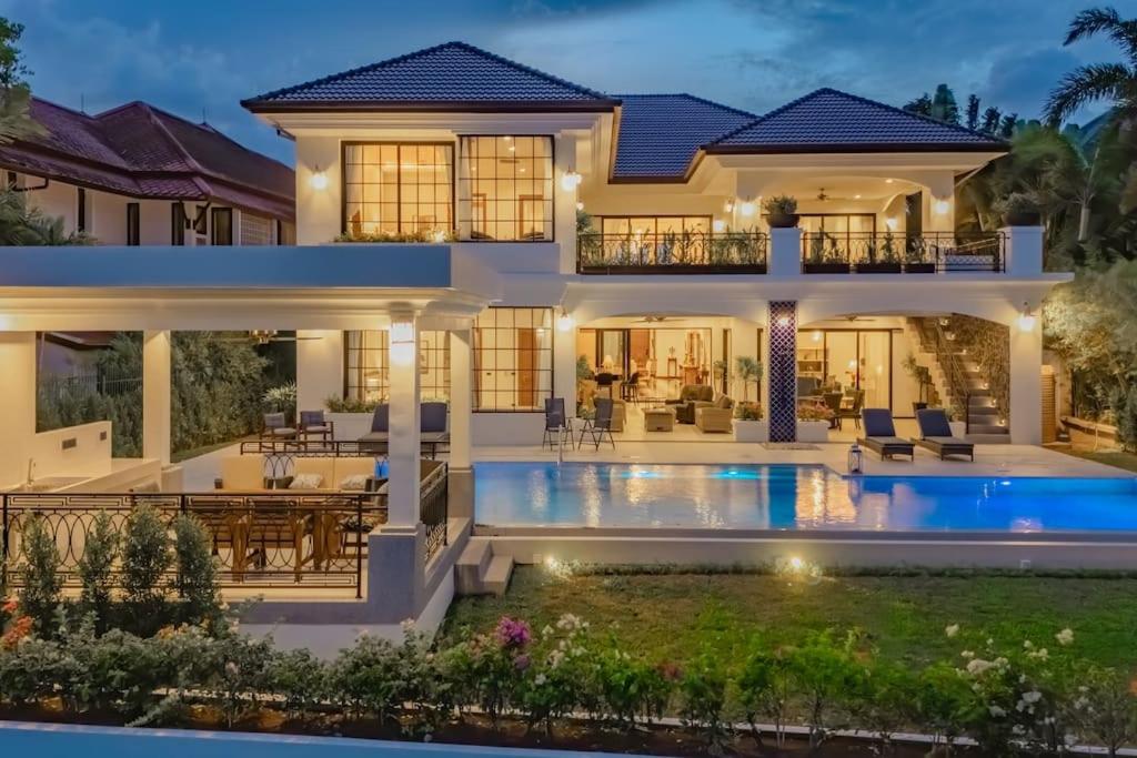 a house with a swimming pool in front of it at Villa Viola 7 Bedroom, Fully Staffed, on the Golf Course in Laguna Phuket